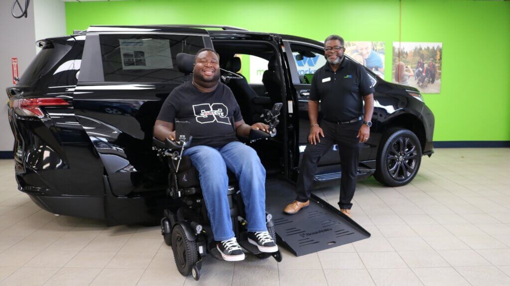 Eric LeGrand in front of a wheelchair accessible vehicle.